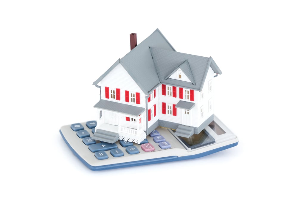 Miniature house with a calculator against a white background-1