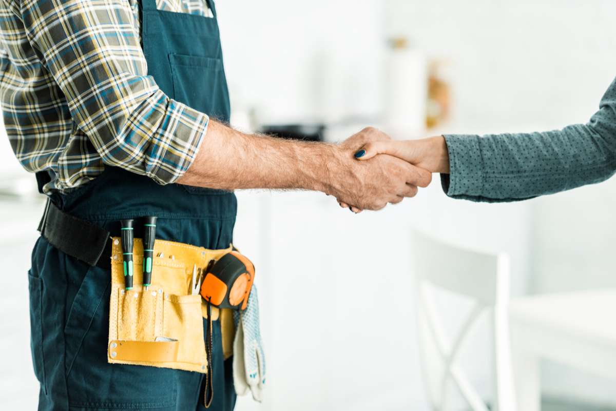 Cropped image of plumber and client shaking hands in kitchen